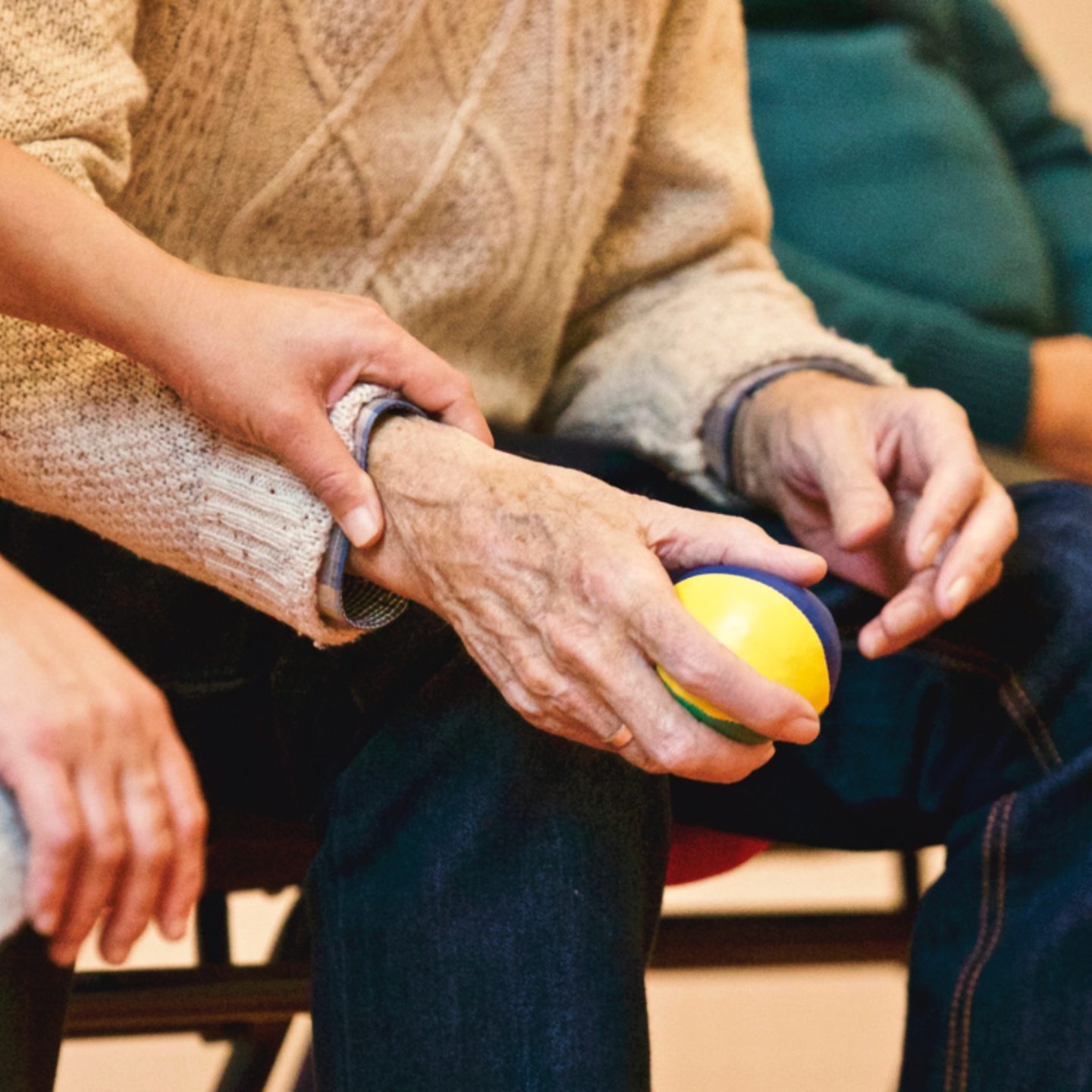 Woman holding wrist of elderly man, both sitting